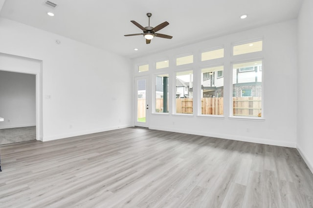 unfurnished living room with a wealth of natural light, recessed lighting, baseboards, and wood finished floors