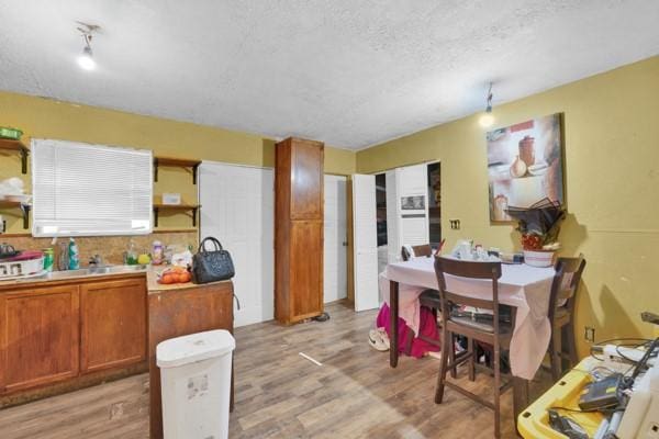 kitchen with brown cabinets, light countertops, a textured ceiling, light wood-type flooring, and open shelves