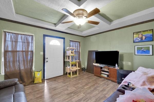 living room with light wood-style floors, coffered ceiling, and ornamental molding