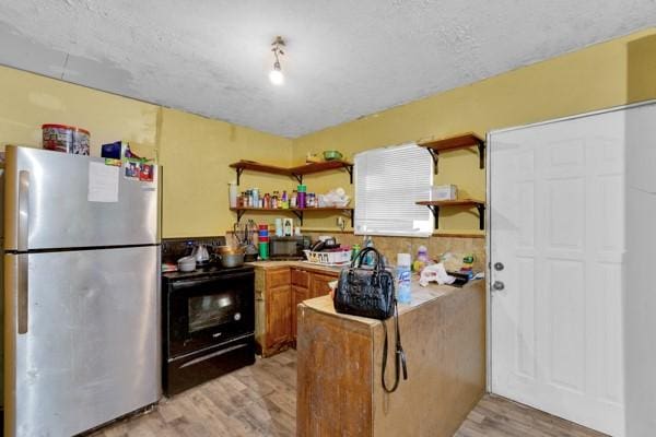 kitchen with light wood-type flooring, freestanding refrigerator, black electric range, and open shelves