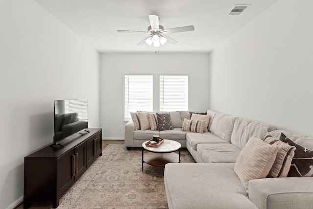 living room with baseboards, visible vents, and a ceiling fan