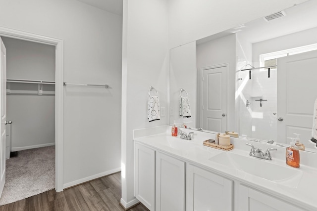 full bath featuring wood finished floors, a sink, a walk in closet, and a shower stall