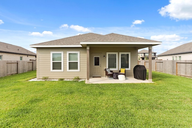 back of house with a fenced backyard, roof with shingles, a lawn, and a patio