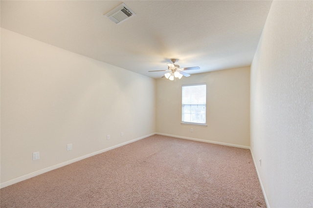 spare room featuring a ceiling fan, light colored carpet, visible vents, and baseboards