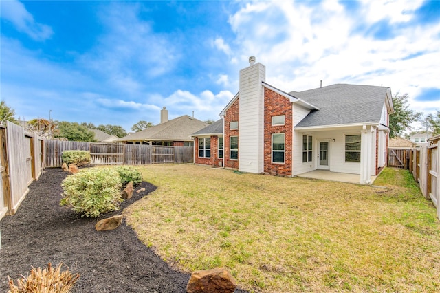 back of house with a lawn, a fenced backyard, a chimney, a patio area, and brick siding