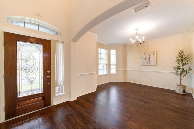 foyer featuring arched walkways, hardwood / wood-style floors, ornamental molding, and visible vents