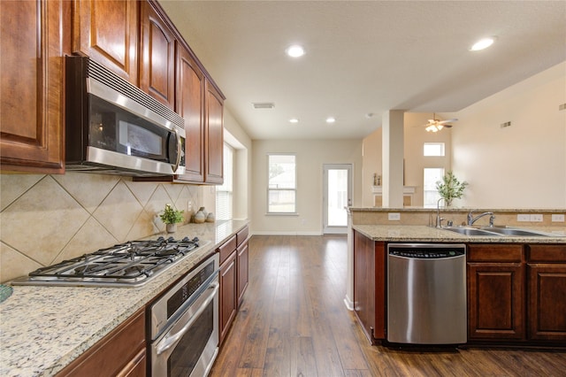 kitchen with a sink, visible vents, appliances with stainless steel finishes, decorative backsplash, and dark wood finished floors