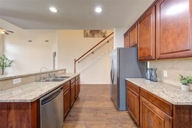 kitchen featuring stainless steel appliances, a sink, a ceiling fan, decorative backsplash, and dark wood-style floors