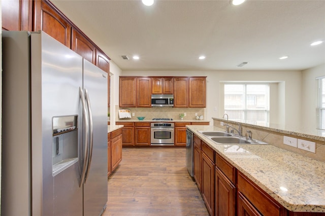 kitchen featuring visible vents, appliances with stainless steel finishes, dark wood-style flooring, a sink, and backsplash