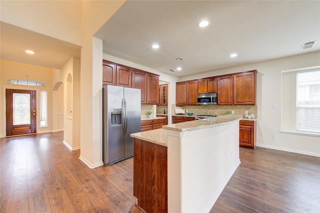 kitchen with tasteful backsplash, a center island with sink, baseboards, dark wood finished floors, and stainless steel appliances