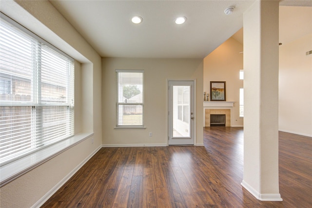 interior space featuring baseboards, dark wood finished floors, a tiled fireplace, and recessed lighting