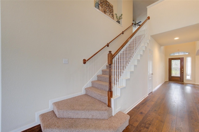 foyer entrance with dark wood-style floors, stairway, a towering ceiling, and baseboards