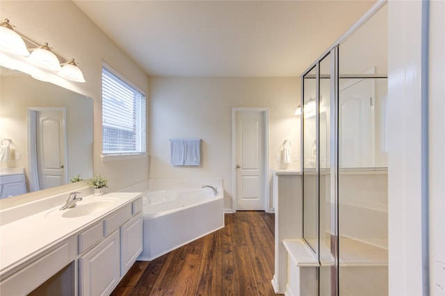 full bathroom with a bath, wood finished floors, and vanity