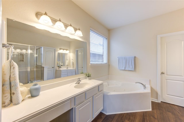 full bath with a stall shower, wood finished floors, vanity, and a jetted tub