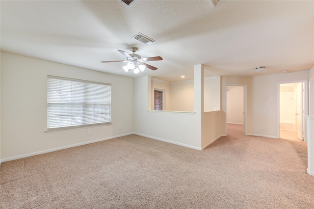 unfurnished room with visible vents, a ceiling fan, light carpet, a textured ceiling, and baseboards