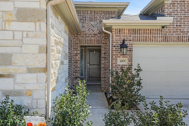 entrance to property with a garage and brick siding