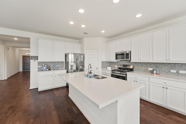 kitchen with appliances with stainless steel finishes, an island with sink, a sink, and white cabinets