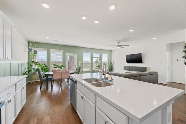 kitchen featuring light countertops, stainless steel dishwasher, dark wood-style flooring, and a sink