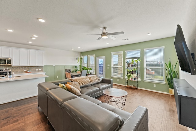 living room featuring a textured ceiling, ceiling fan, recessed lighting, dark wood-style flooring, and visible vents