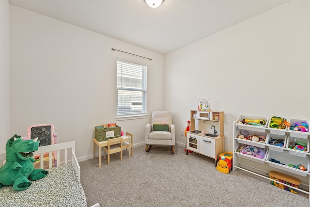 recreation room featuring light carpet and baseboards