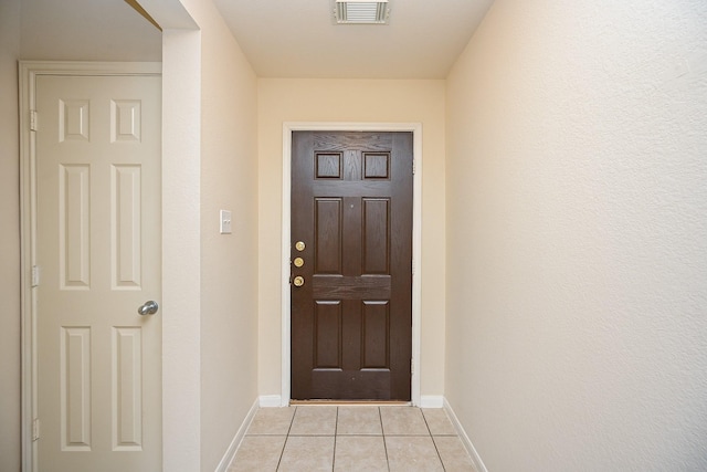 doorway to outside with light tile patterned floors, visible vents, and baseboards