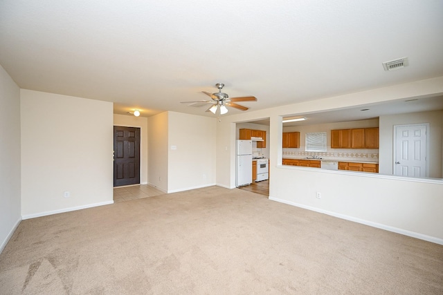 unfurnished living room featuring baseboards, visible vents, ceiling fan, and light colored carpet