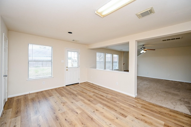 spare room with ceiling fan, light wood finished floors, visible vents, and baseboards