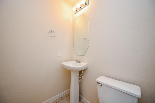 half bath with tile patterned flooring, toilet, and baseboards