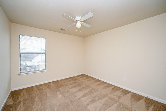 empty room with baseboards, a ceiling fan, visible vents, and light colored carpet