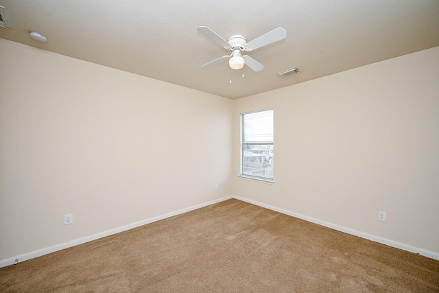 spare room featuring a ceiling fan, carpet, visible vents, and baseboards