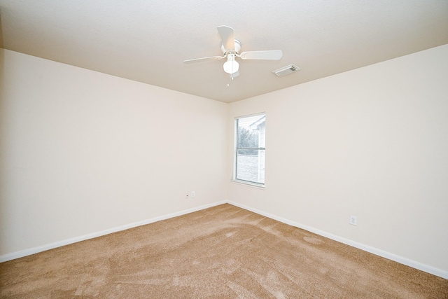 spare room with baseboards, a ceiling fan, visible vents, and light colored carpet