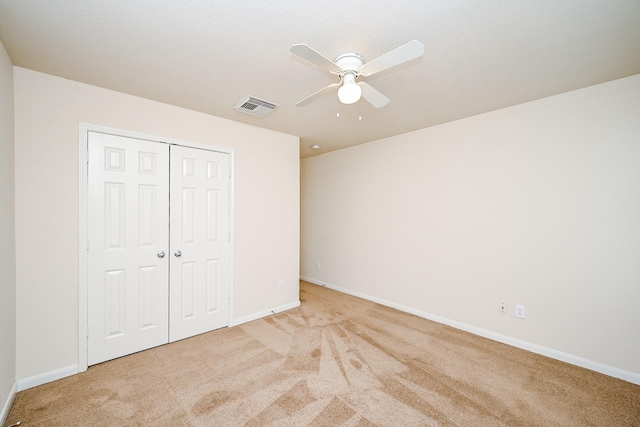 unfurnished bedroom featuring baseboards, a closet, visible vents, and light colored carpet