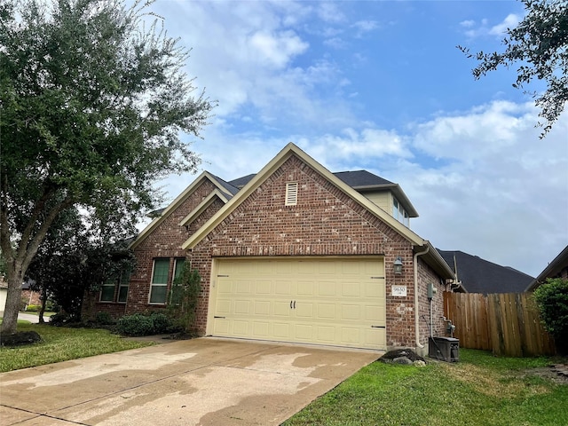 traditional-style house with brick siding, an attached garage, a front yard, fence, and driveway