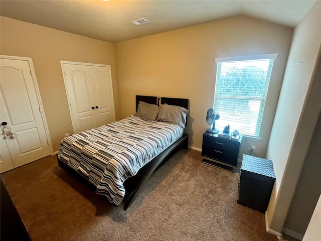 bedroom with carpet floors, lofted ceiling, and visible vents