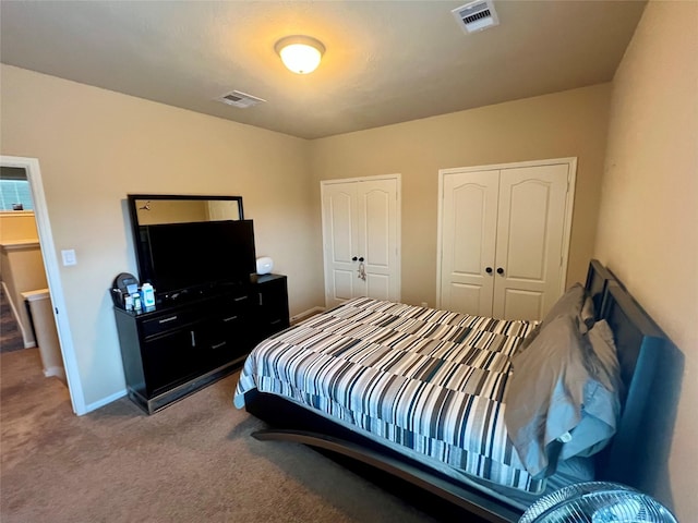 carpeted bedroom with two closets, visible vents, and baseboards