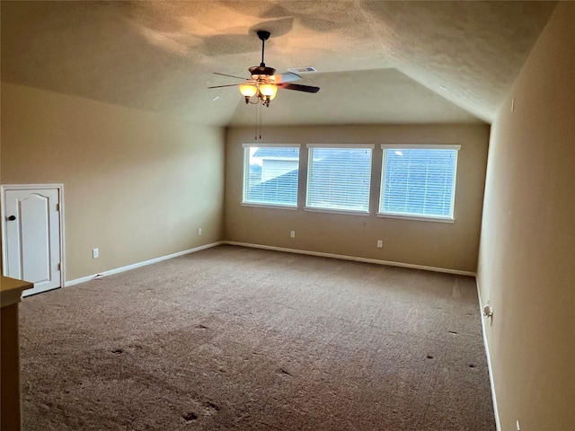 spare room with carpet, vaulted ceiling, a textured ceiling, and baseboards