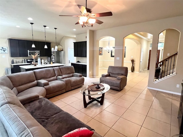 living area with ceiling fan, stairs, arched walkways, and light tile patterned flooring