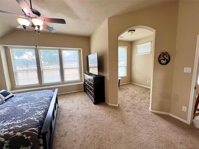 bedroom featuring arched walkways, baseboards, a ceiling fan, and light colored carpet