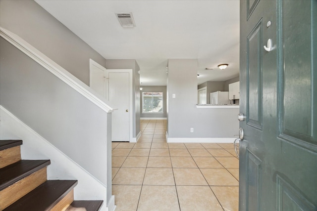 foyer entrance featuring light tile patterned floors, stairway, visible vents, and baseboards