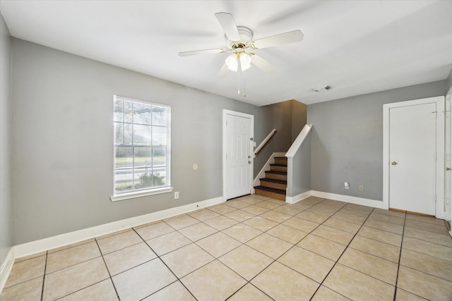 empty room with a ceiling fan, stairway, baseboards, and light tile patterned floors