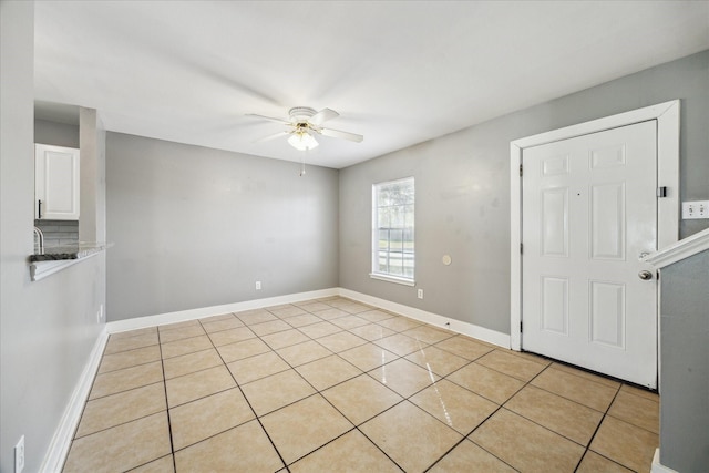 empty room featuring ceiling fan, baseboards, and light tile patterned floors