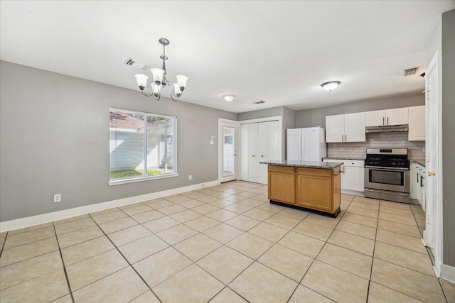 kitchen featuring under cabinet range hood, freestanding refrigerator, a center island, tasteful backsplash, and gas stove