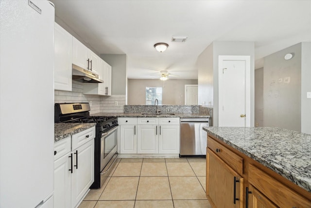 kitchen with light tile patterned flooring, under cabinet range hood, stainless steel appliances, a sink, and visible vents