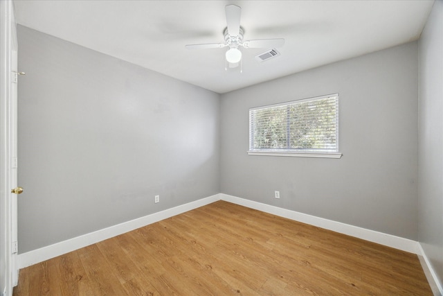 spare room with baseboards, ceiling fan, visible vents, and light wood finished floors