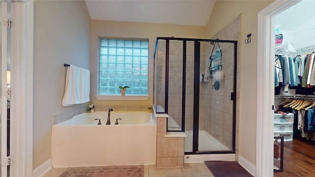 full bathroom featuring a stall shower, a walk in closet, and a bath