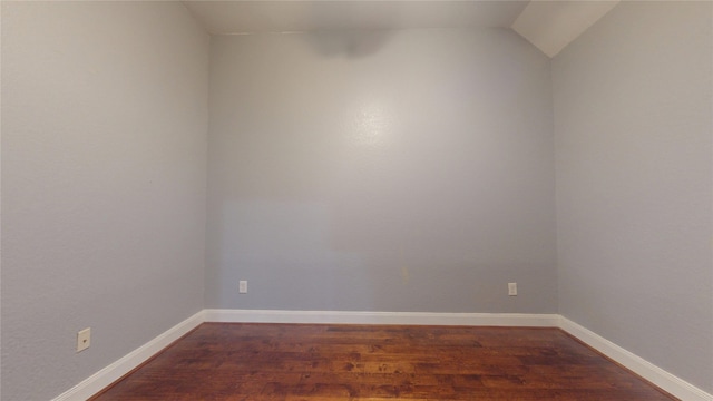 unfurnished room with lofted ceiling, dark wood-style floors, and baseboards