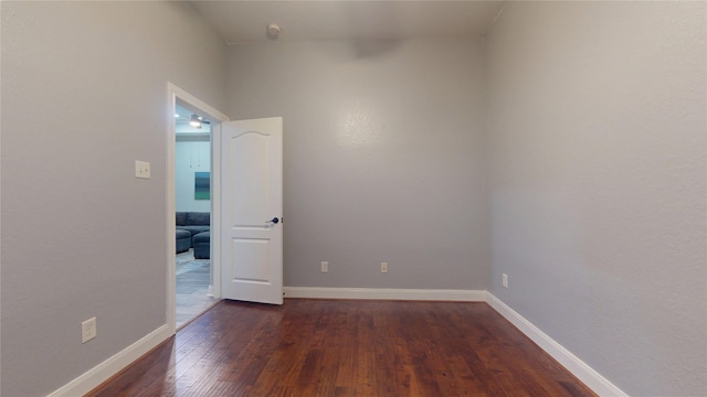 spare room with baseboards and dark wood-style flooring