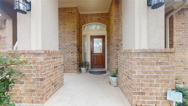 view of exterior entry featuring brick siding and stucco siding