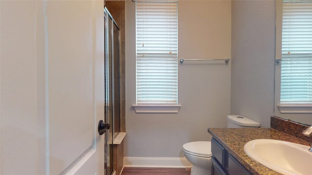 bathroom with baseboards, toilet, wood finished floors, vanity, and a shower stall