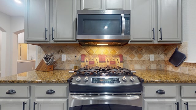 kitchen with stainless steel appliances, stone countertops, and backsplash